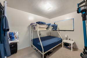 Bedroom featuring light carpet and a textured ceiling