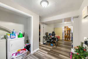 Interior space featuring wood-type flooring, a textured ceiling, and independent washer and dryer