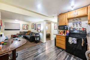 Kitchen featuring dark hardwood / wood-style flooring, black appliances, a textured ceiling, and light brown cabinets