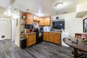 Kitchen featuring black appliances, dark hardwood / wood-style floors, a textured ceiling, and washer / clothes dryer