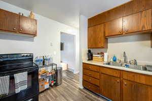 Kitchen featuring electric range, light wood-type flooring, and sink