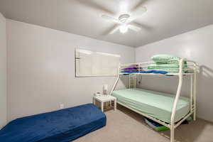 Carpeted bedroom with ceiling fan and a textured ceiling