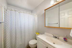 Bathroom with a shower with curtain, vanity, and toilet