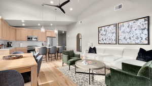 Living room featuring high vaulted ceiling, light hardwood / wood-style flooring, and ceiling fan