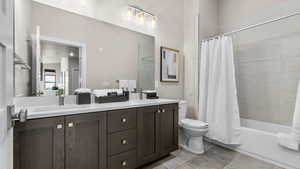 Full bathroom with vanity, shower / bath combo, and toilet