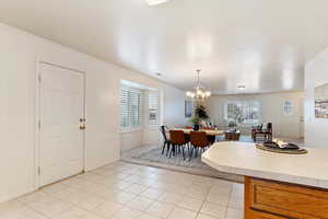 Dining space with a wealth of natural light, light tile patterned floors, and an inviting chandelier