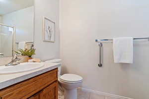 Bathroom featuring tile patterned flooring, vanity, toilet, and walk in shower