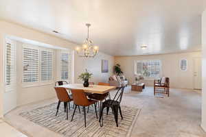 Carpeted dining area with an inviting chandelier