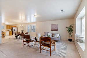 Carpeted living room featuring an inviting chandelier