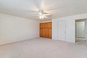 Unfurnished bedroom with ceiling fan and light colored carpet