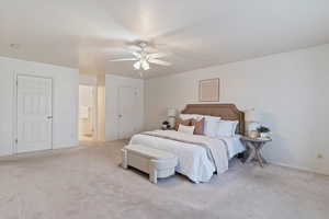 Bedroom featuring ceiling fan, light colored carpet, and ensuite bathroom