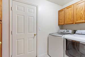 Washroom featuring cabinets, light tile patterned floors, and washing machine and dryer