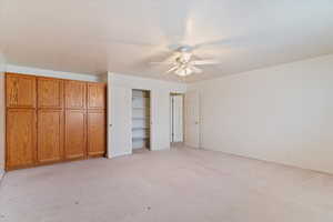 Unfurnished bedroom with light colored carpet and ceiling fan