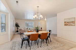 Dining space with light carpet and an inviting chandelier