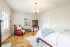 Bedroom with a notable chandelier, wood-type flooring, and radiator