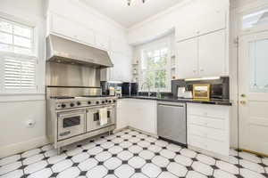 Kitchen with white cabinets, sink, ornamental molding, and stainless steel appliances