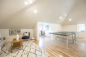 Recreation room featuring light hardwood / wood-style flooring and vaulted ceiling