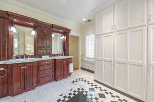 Bathroom featuring tile patterned floors, a tub, crown molding, and vanity