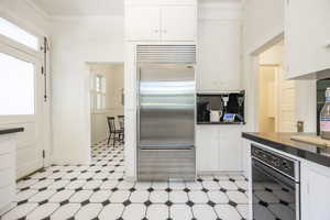 Kitchen with built in fridge, plenty of natural light, and white cabinetry