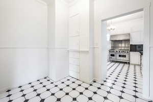 Kitchen featuring white cabinets, pendant lighting, an inviting chandelier, and double oven range