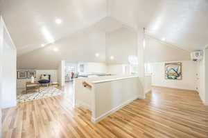 Bonus room with light hardwood / wood-style floors, vaulted ceiling, and a wall mounted AC