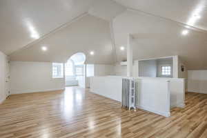 Bonus room featuring light hardwood / wood-style flooring, radiator, and vaulted ceiling