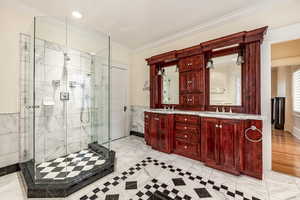 Bathroom with crown molding, a shower with door, and vanity