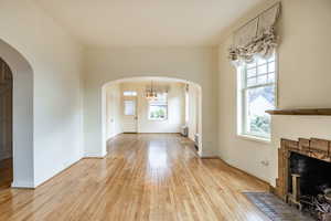 Living room featuring radiator, a chandelier, a fireplace, and light hardwood / wood-style floors