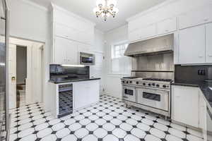 Kitchen with white cabinetry, backsplash, appliances with stainless steel finishes, and an inviting chandelier