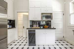 Kitchen featuring built in appliances and white cabinets