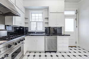 Kitchen featuring decorative backsplash, white cabinetry, sink, and stainless steel appliances