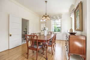 Dining space featuring light hardwood / wood-style flooring, ornamental molding, and an inviting chandelier