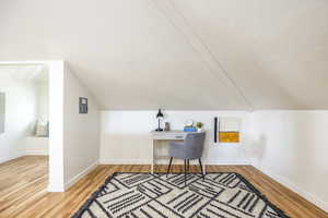 Office space with hardwood / wood-style floors and lofted ceiling