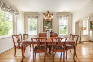 Dining room with crown molding, light wood-type flooring, and a notable chandelier