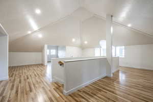 Additional living space with light hardwood / wood-style flooring and lofted ceiling