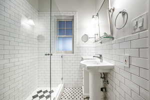 Bathroom featuring tile patterned flooring, a tile shower, and tile walls