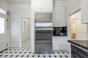 Kitchen featuring white cabinetry, stainless steel built in fridge, and a healthy amount of sunlight