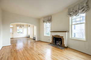 Unfurnished living room with a fireplace, light hardwood / wood-style floors, and a chandelier