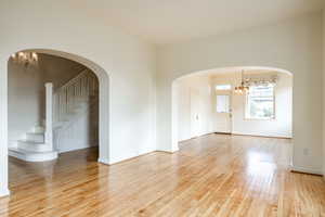 Empty room with a chandelier and wood-type flooring