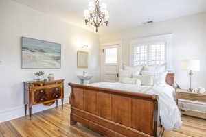 Bedroom with a notable chandelier and light wood-type flooring