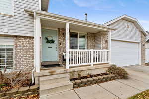 Property entrance with covered porch and a garage