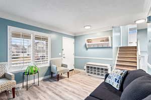 Sitting room featuring a textured ceiling, light hardwood / wood-style floors, and crown molding