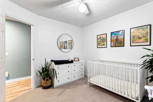 Bedroom featuring a crib, carpet, and ceiling fan