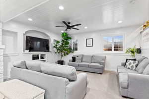 Living room featuring wood ceiling, ceiling fan, and light colored carpet