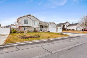 Tri-level home with covered porch, a garage, and a front yard