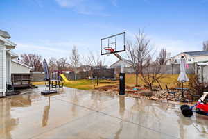 View of basketball court featuring a trampoline, a playground, and a yard