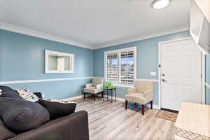 Living area with light hardwood / wood-style flooring and ornamental molding