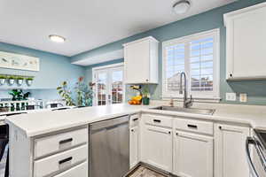 Kitchen with kitchen peninsula, stainless steel appliances, white cabinetry, and sink