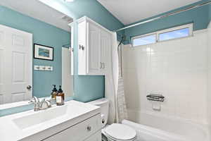 Full bathroom featuring vanity, toilet, a textured ceiling, and shower / tub combo with curtain