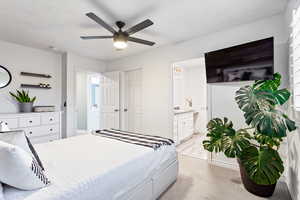 Carpeted bedroom with connected bathroom and ceiling fan